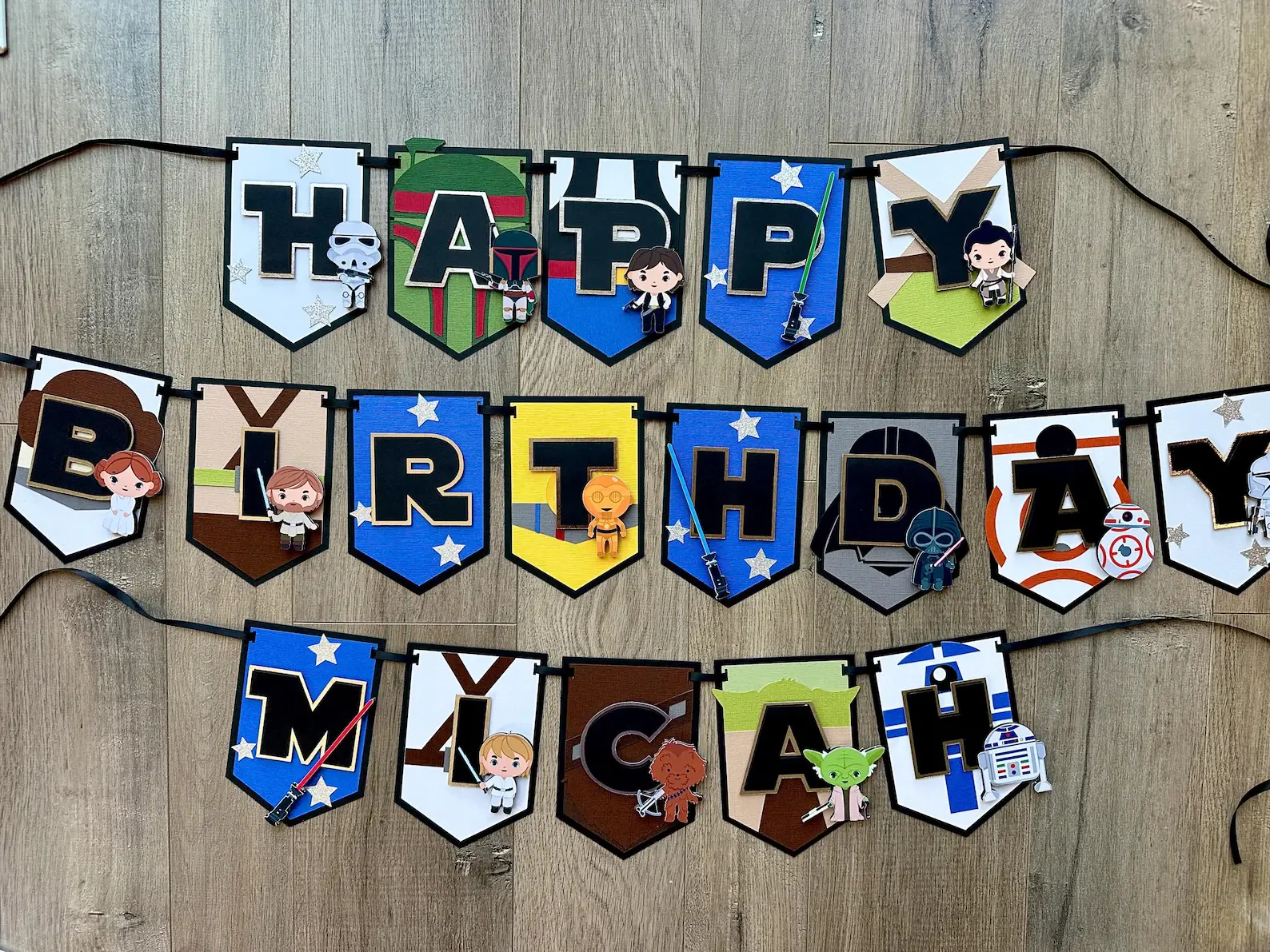 Full Happy Birthday Micah banner laid out in three rows on a wood floor